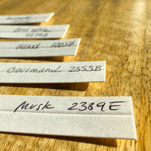 set of fragrance blotters with handwritten labels showing musk gourmand wood